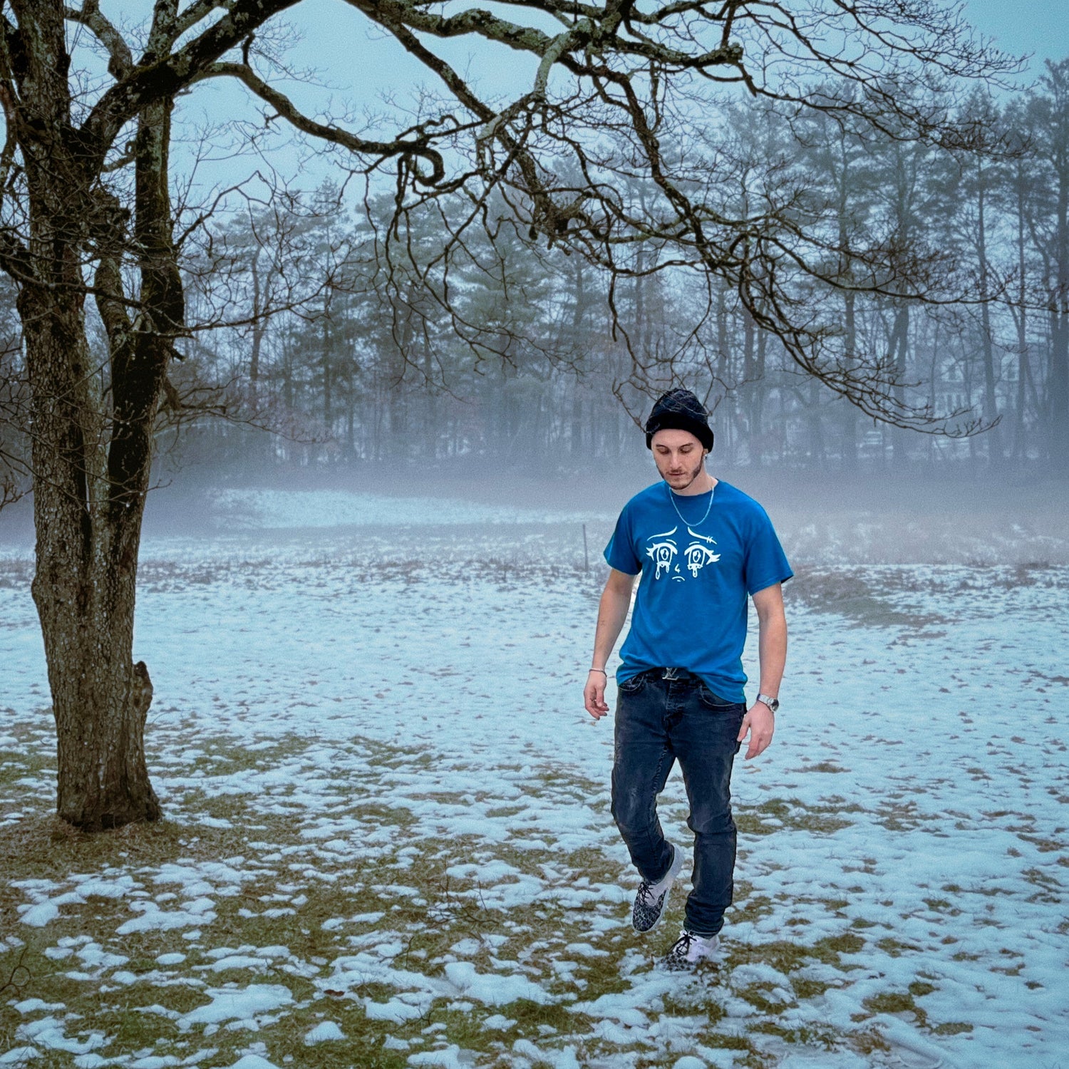 Radley walking in a snowy field with trees and fog in the background